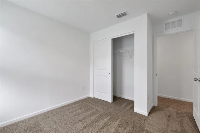 a view of an empty room with closet and wooden floor