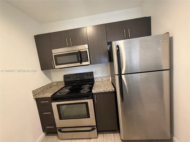 a kitchen with granite countertop a refrigerator and a stove top oven
