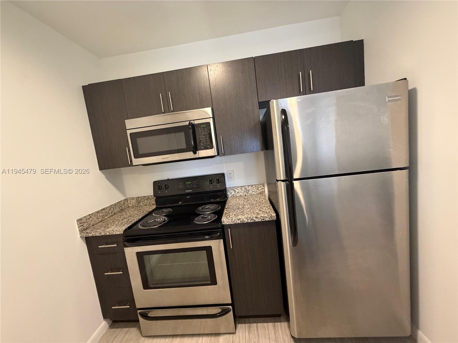 1801 Southwest 32nd Avenue, Unit 701 Miami, FL 33145 - Photo 6 of 13 a kitchen with granite countertop a refrigerator and a stove top oven