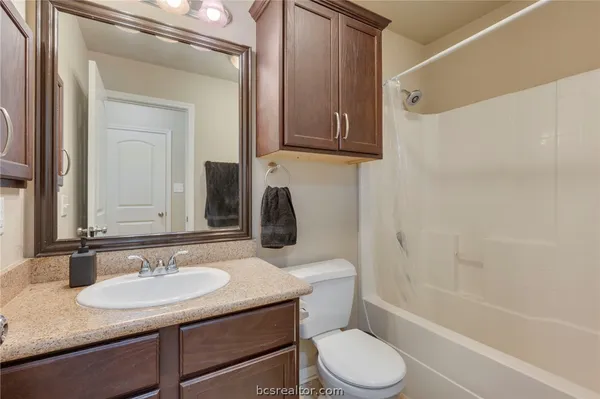 a bathroom with a granite countertop sink toilet a mirror and shower