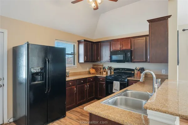 a kitchen with granite countertop a sink refrigerator and cabinets