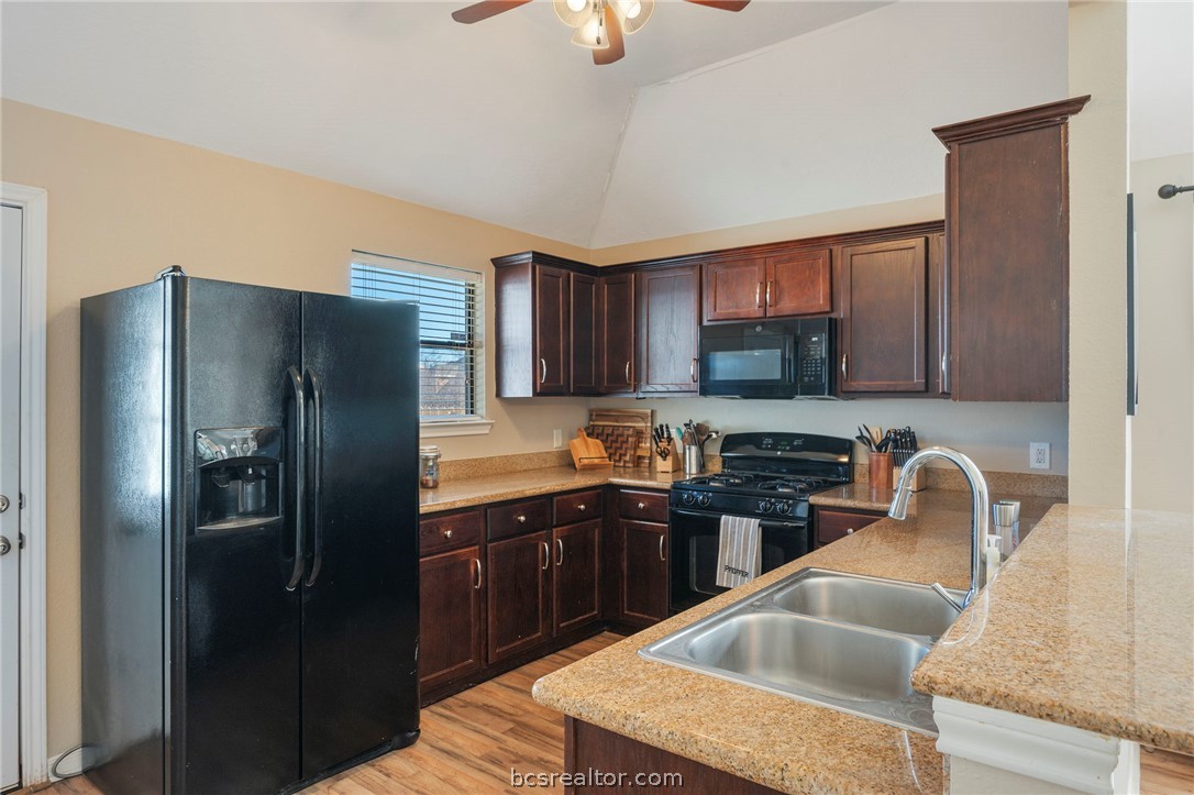 2000 Turning Leaf Drive Bryan, TX 77807 - Photo 6 of 20 a kitchen with granite countertop a sink refrigerator and cabinets
