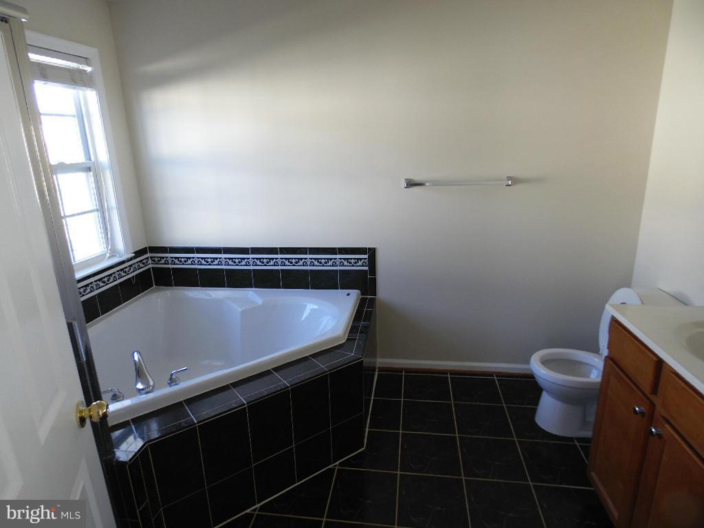 9705 Langley Road Baltimore, MD 21220 - Photo 13 of 26 a bathroom with a toilet a sink a window and mirror