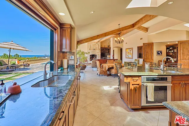 a kitchen with stainless steel appliances granite countertop a stove and a view of living room