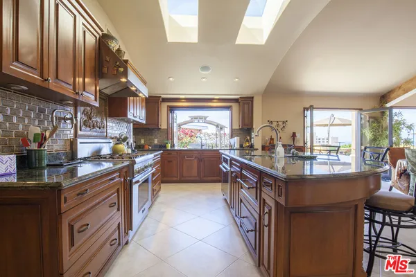 a kitchen with stainless steel appliances granite countertop a stove a sink and a refrigerator