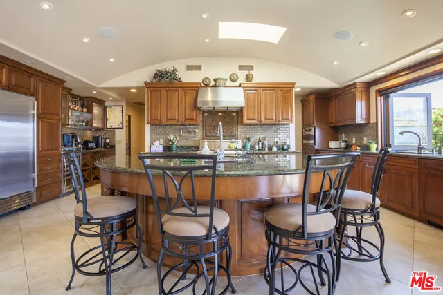a dining room with stainless steel appliances kitchen island granite countertop a dining table chairs and a refrigerator