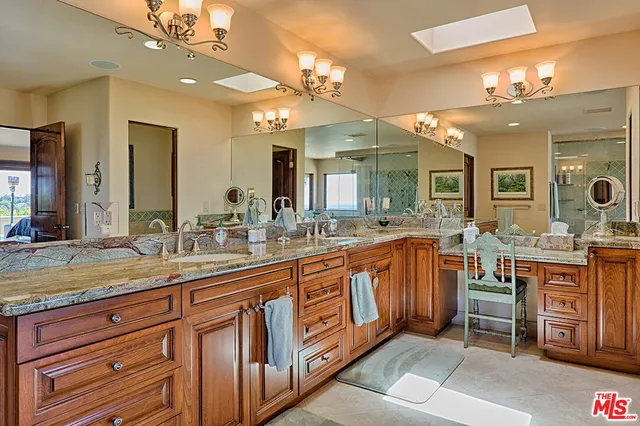 a large kitchen with kitchen island granite countertop lots of white cabinets a sink and dishwasher