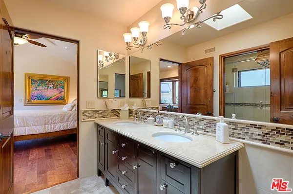 a en suite bathroom with a sink double vanity granite and a large mirror