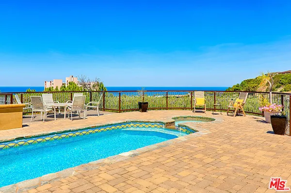 a view of a swimming pool with an outdoor seating and house in the background