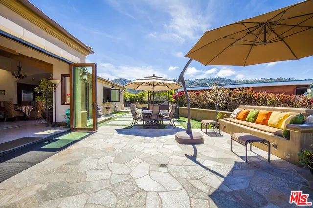 a view of a patio with a table and chairs under an umbrella