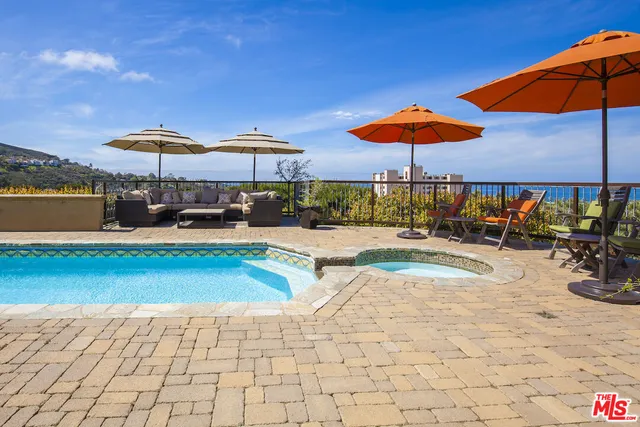 a view of a swimming pool with a table and chairs under an umbrella