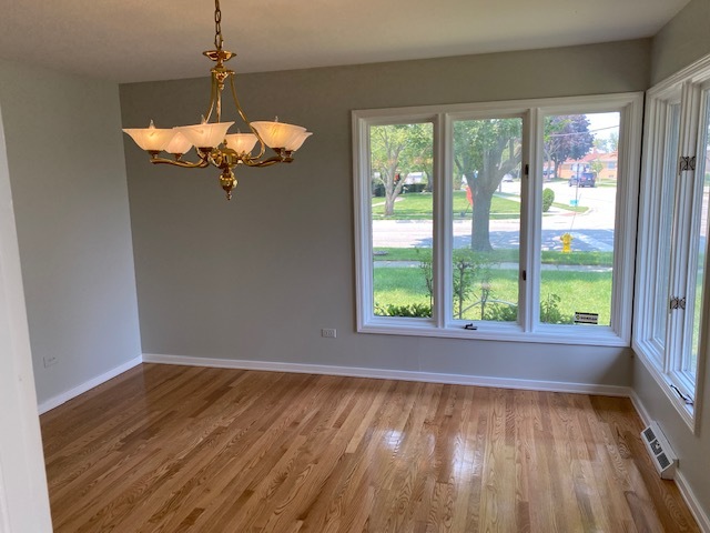 7037 West Main Street Niles, IL 60714 - Photo 11 of 29 a view of a room with wooden floor exposed radiator and windows