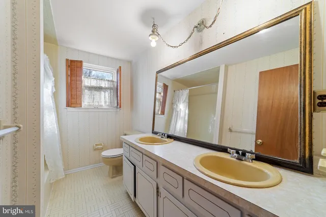 a bathroom with a granite countertop double vanity sinks a mirror and a toilet
