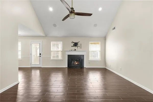 a view of an empty room with wooden floor fireplace and a window