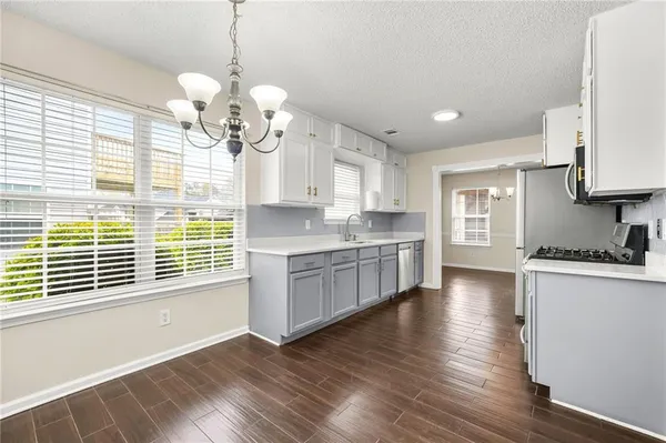 a large kitchen with stainless steel appliances granite countertop a stove a sink and white cabinets with wooden floor