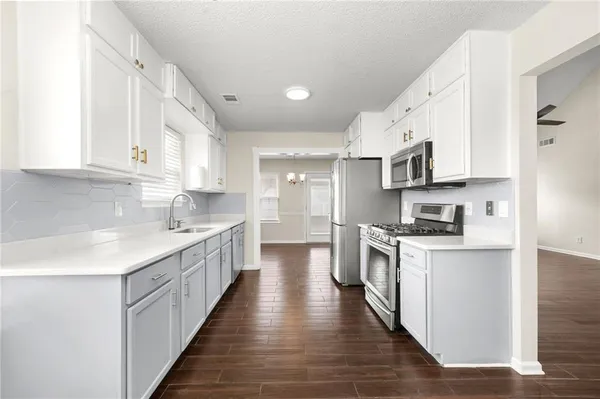 a kitchen with stainless steel appliances granite countertop a stove top oven a sink dishwasher and a refrigerator