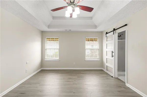 an empty room with wooden floor chandelier fan and windows