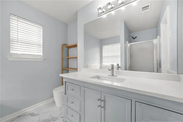 a bathroom with a toilet a sink a vanity a window and mirror