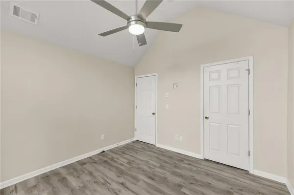 an empty room with wooden floor ceiling fan and windows
