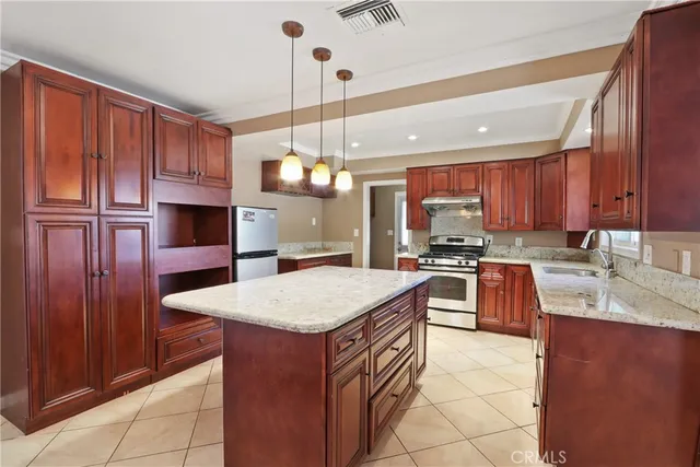 a kitchen with kitchen island granite countertop wooden cabinets a center island a stove and a chandelier