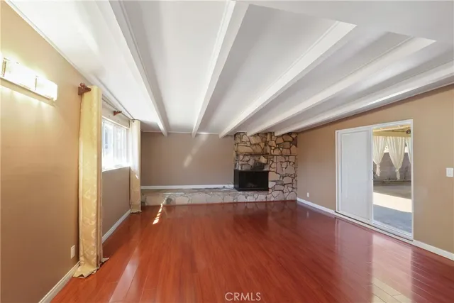 a view of empty room with wooden floor and fireplace