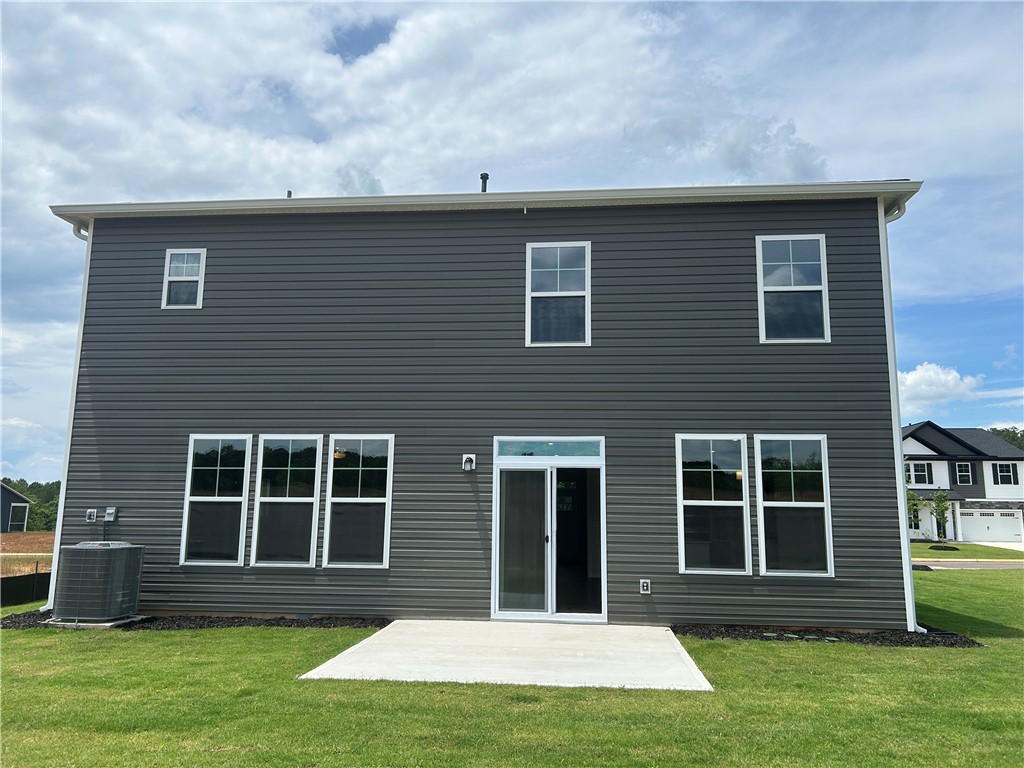 217 Bellflower Lane Anderson, SC 29625 - Photo 13 of 27 A newly constructed home features dark gray siding and white-framed windows, with a concrete patio overlooking a grassy yard.