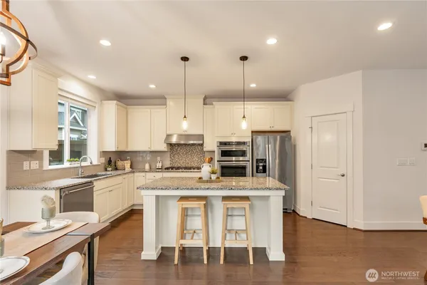 a kitchen with stainless steel appliances kitchen island granite countertop a stove a sink and a refrigerator