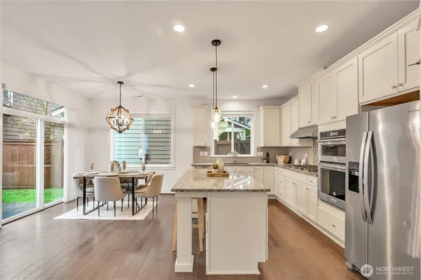 a kitchen with kitchen island granite countertop a table chairs stove and refrigerator
