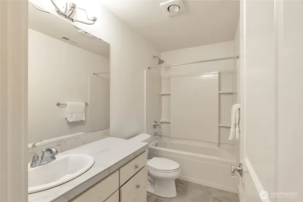 a bathroom with a bathtub shower sink mirror vanity and a toilet
