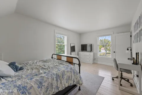 a bedroom with a bed a chair and a large window