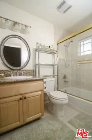 a bathroom with a granite countertop toilet sink and mirror