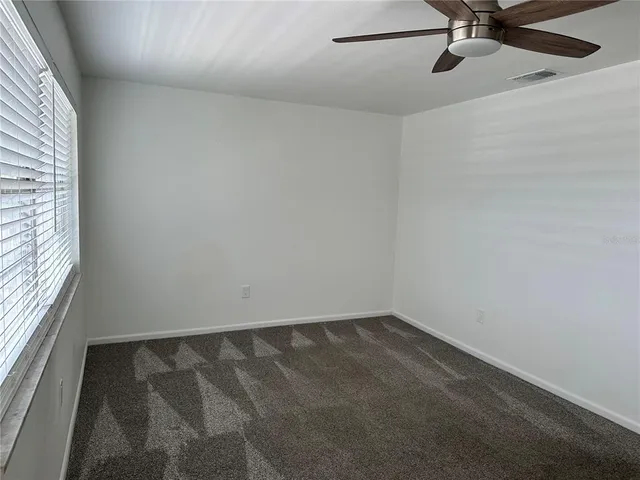 an empty room with a window and a fan