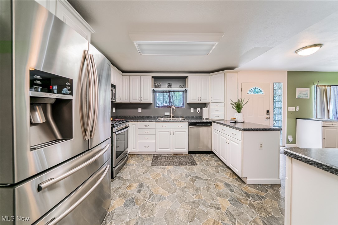 6873 Lake Road Madison, OH 44057 - Photo 10 of 29 Kitchen with appliances with stainless steel finishes, light stone finish flooring, white cabinetry, and a peninsula