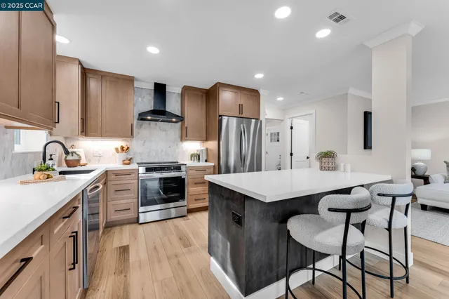 a kitchen with stainless steel appliances kitchen island granite countertop a table chairs sink refrigerator and cabinets