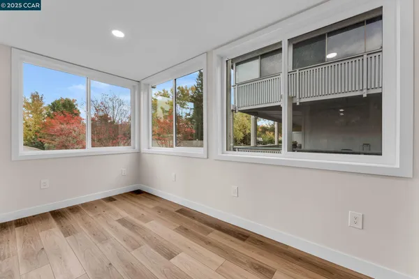 a view of empty room with wooden floor and fan
