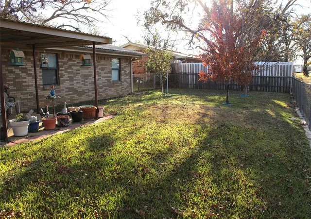 a backyard of a house with wooden fence and large trees