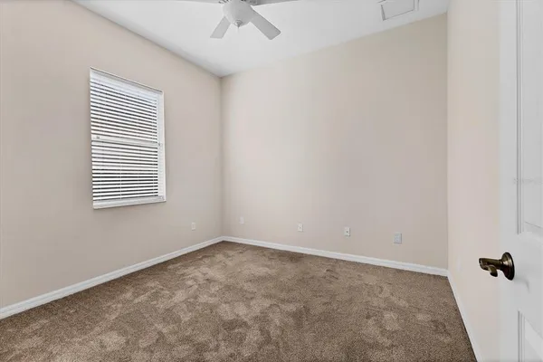 an empty room with a window and a ceiling fan