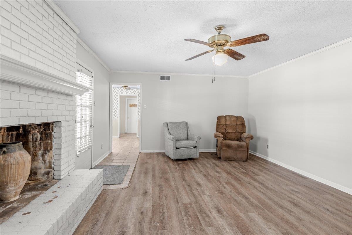 436 Sterling Drive Collierville, TN 38017 - Photo 24 of 40 Sitting room with a brick fireplace, ornamental molding, light wood-style flooring, a textured ceiling, and ceiling fan