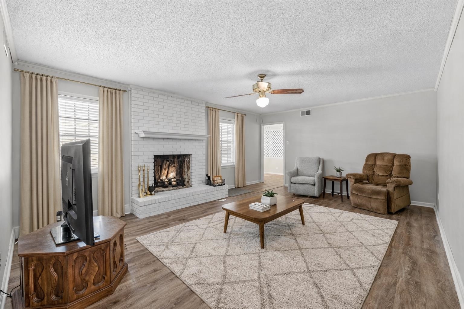 436 Sterling Drive Collierville, TN 38017 - Photo 25 of 40 Living room featuring wood finished floors, a ceiling fan, a fireplace, a textured ceiling, and crown molding