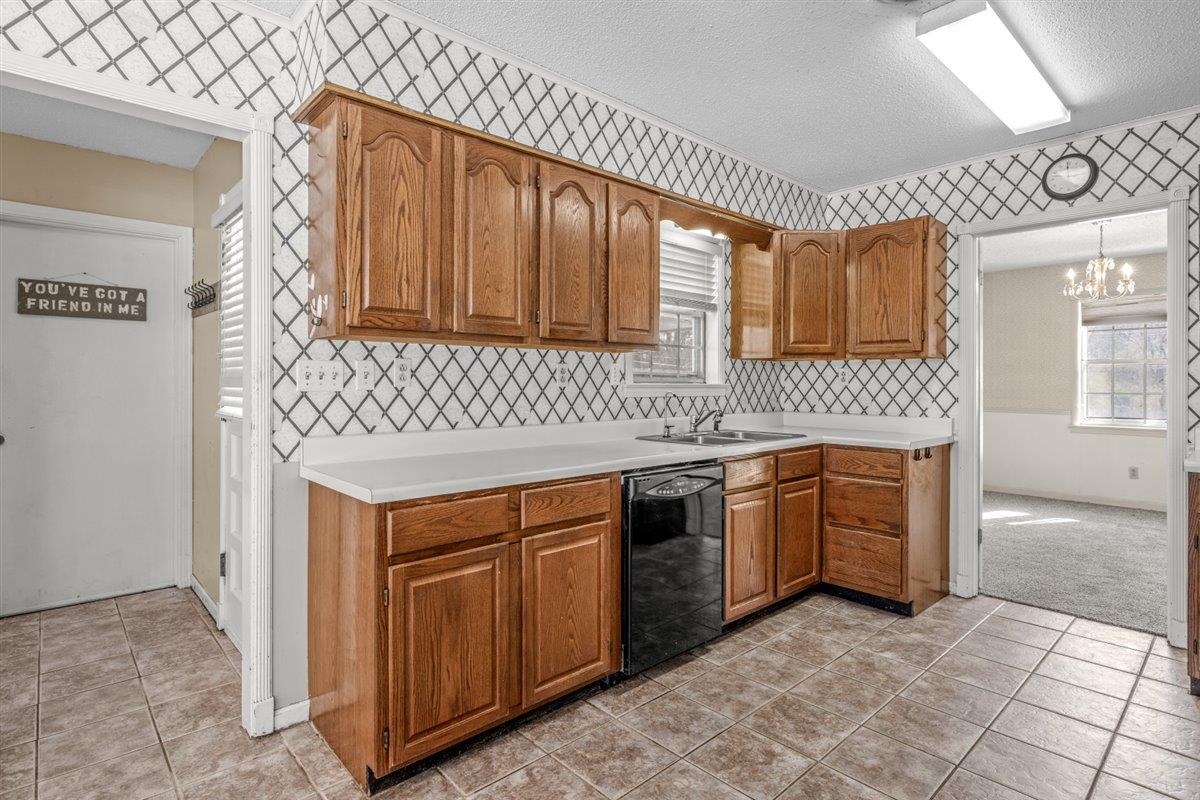 436 Sterling Drive Collierville, TN 38017 - Photo 28 of 40 Kitchen with brown cabinetry, light countertops, black dishwasher, light tile patterned flooring, and a chandelier