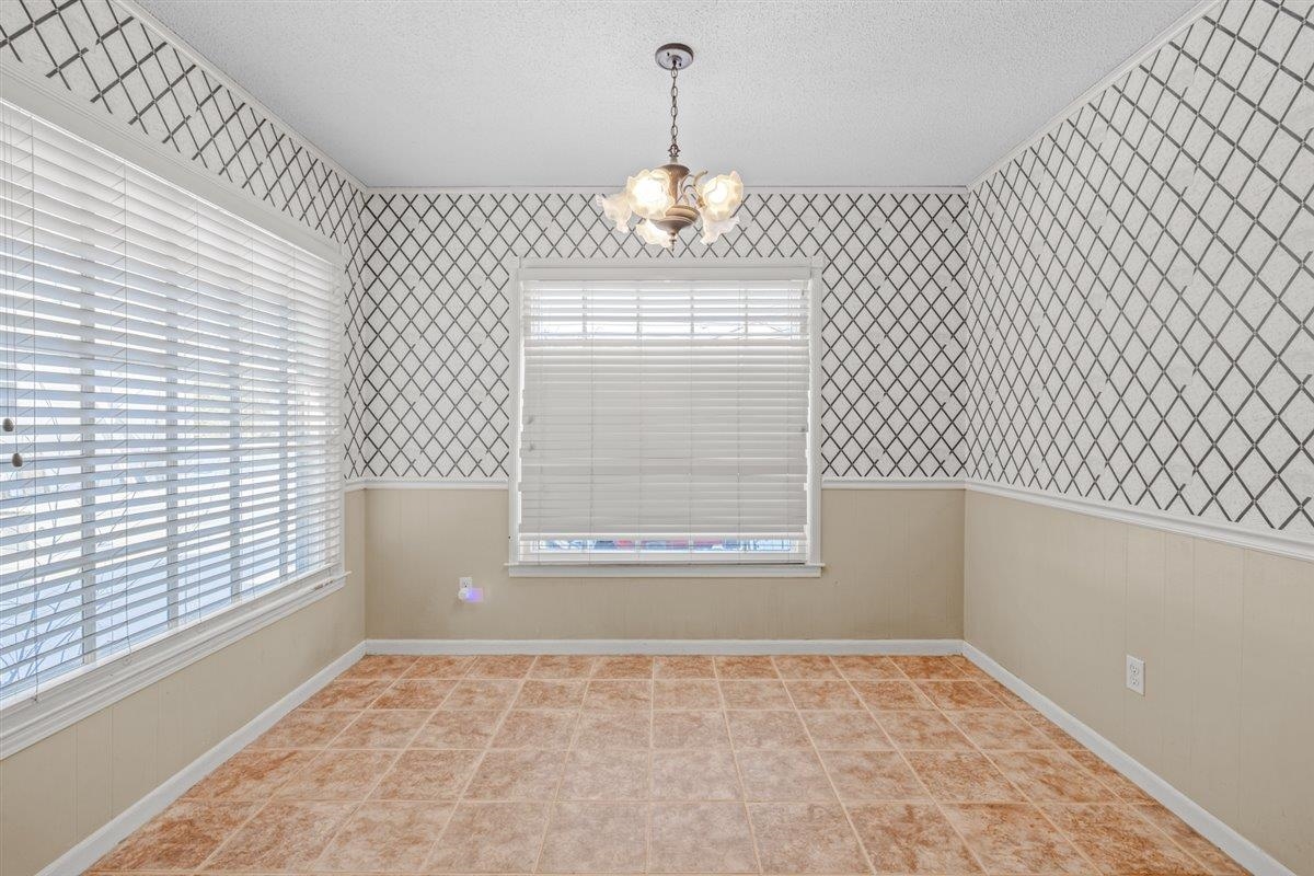 436 Sterling Drive Collierville, TN 38017 - Photo 7 of 40 Unfurnished dining area featuring wainscoting, wallpapered walls, a chandelier, and a textured ceiling