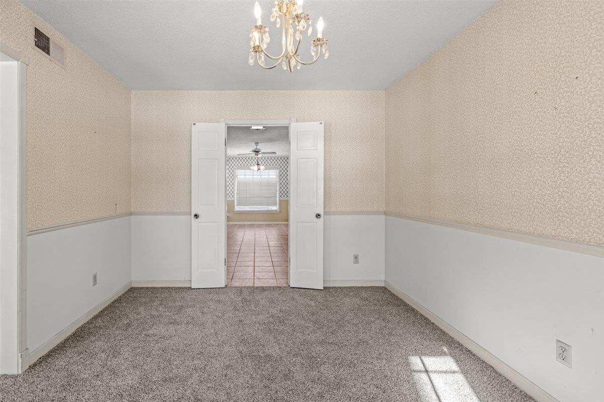 436 Sterling Drive Collierville, TN 38017 - Photo 8 of 40 Carpeted empty room featuring a chandelier, wallpapered walls, and a textured ceiling