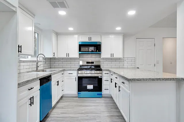 a kitchen with granite countertop a stove top oven sink and cabinets