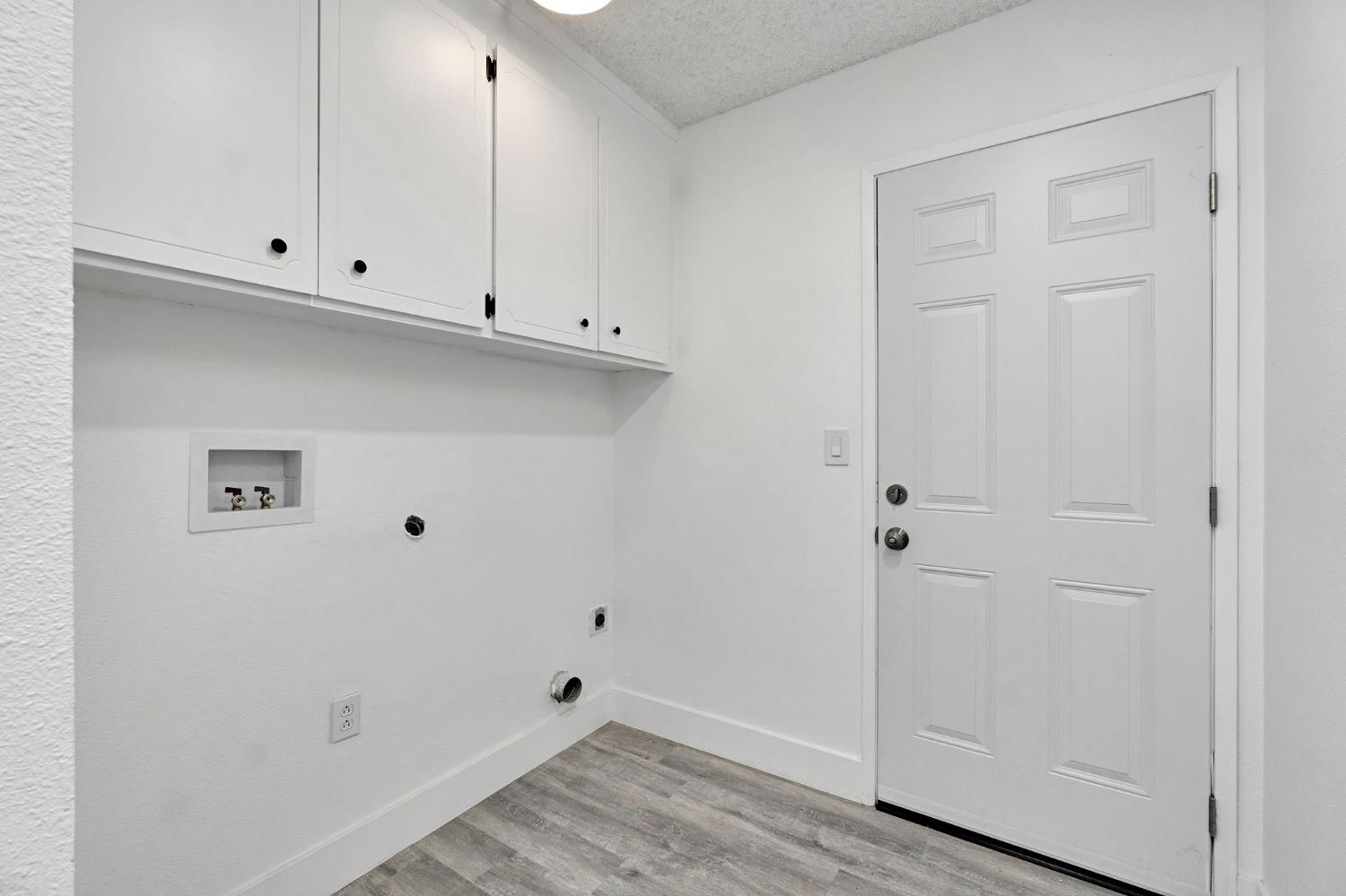 2808 Riverview Drive Madera, CA 93637 - Photo 25 of 35 washroom with a textured ceiling, light wood finished floors, hookup for a washing machine, hookup for an electric dryer, and cabinet space