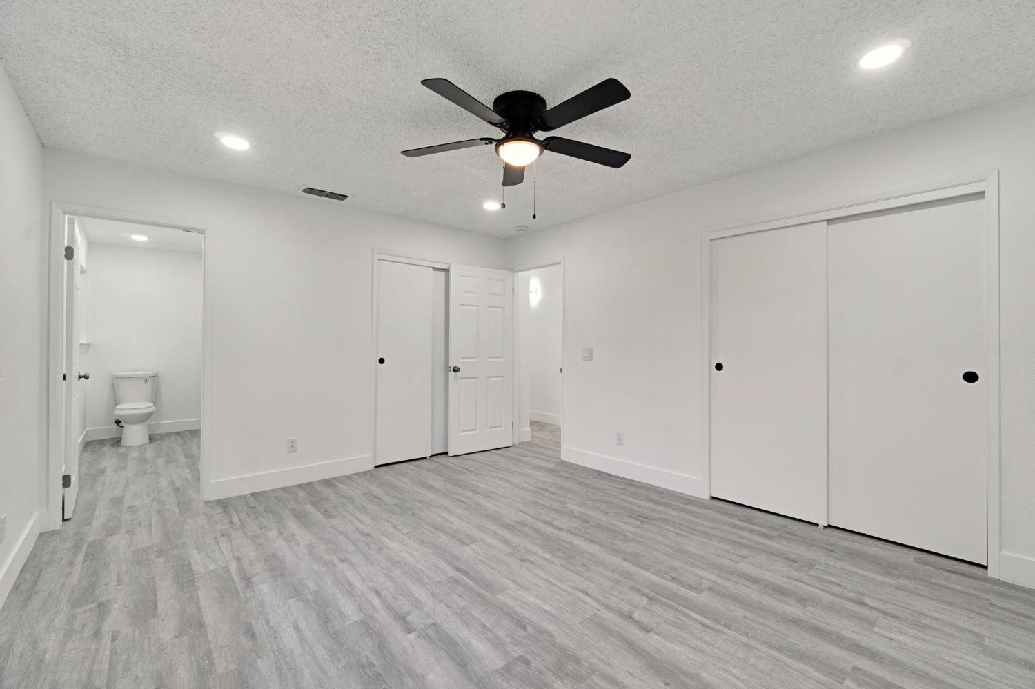 2808 Riverview Drive Madera, CA 93637 - Photo 29 of 35 unfurnished bedroom featuring recessed lighting, a textured ceiling, two closets, light wood finished floors, and a ceiling fan