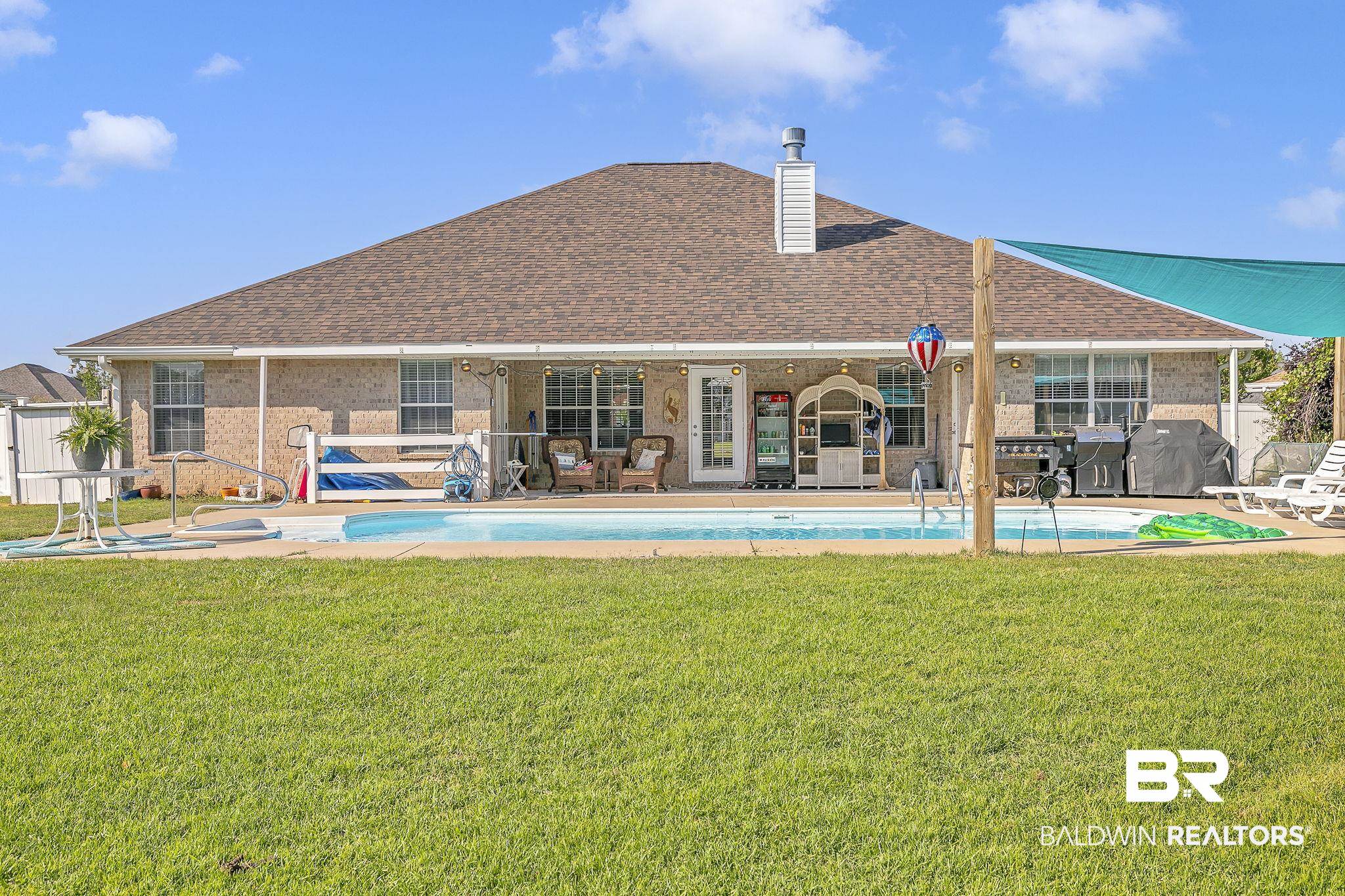 16358 Tempest Drive Foley, AL 36535 - Photo 33 of 46 Back of property featuring a lawn, roof with shingles, an outdoor pool, and brick siding