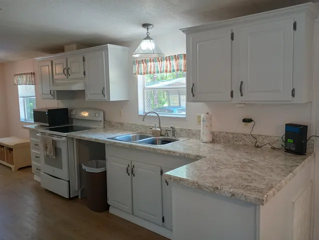 a kitchen with granite countertop a sink white cabinets and a dishwasher