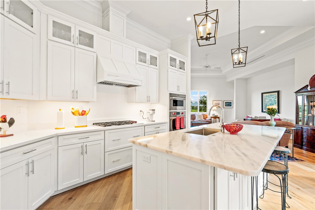 11 Caribe Way Vero Beach, FL 32963 - Photo 11 of 34 a kitchen with stainless steel appliances kitchen island granite countertop a sink dishwasher and white cabinets with wooden floor