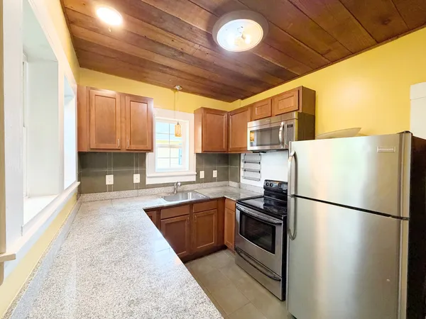 a kitchen with granite countertop stainless steel appliances a refrigerator a sink and cabinets