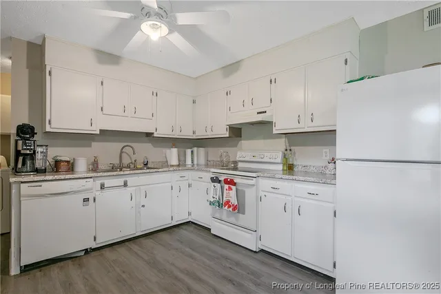 a kitchen with granite countertop white cabinets and white appliances